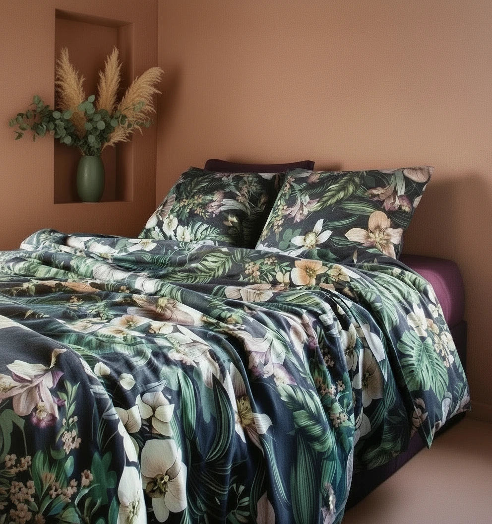 Bed with floral bedding in a room with a vase of flowers on a shelf.