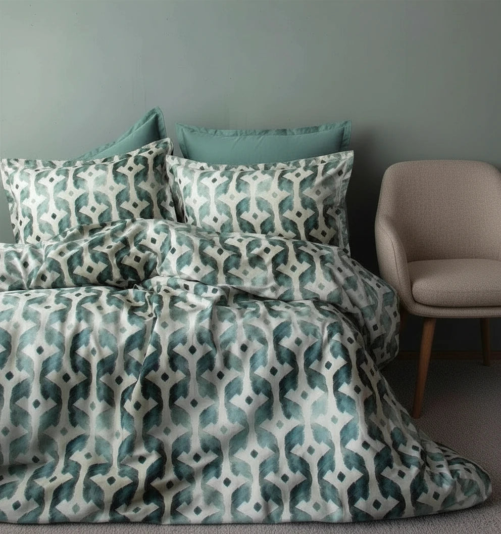 Satin “Batique” bedding set in sage, neatly folded on a neutral surface